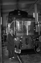 Mann ved Henschel diesel-lokomotiv, inne i lokomotivstallen.