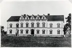 Norrtullskolan i Växjö, 1882. 
Framför byggnaden syns monumentet över domprosten Håkan Sjögren (1727-1815), Växjö.