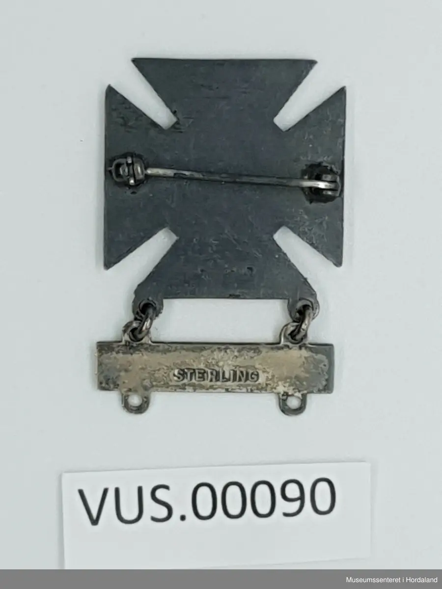 Medalje eller ferdighetsmerke til å feste på uniform. Hoveddelen er et likebeinet kors, nærmest fire trekanter som stikker ut fra sentrum. Medaljens sentrum viser relieff av fire ringer utenfor hverandre, som en blink. Overflaten veksler mellom glatt og ruglete, som også gir effekt i det visuelle utrykket. Festet under korset med med løse ringer, henger en plate med inkripsjonen RIFLE, under platen er det to ringer, som muliggjør feste av flere plater som viser til ulike ferdigheter og våpentyper. 