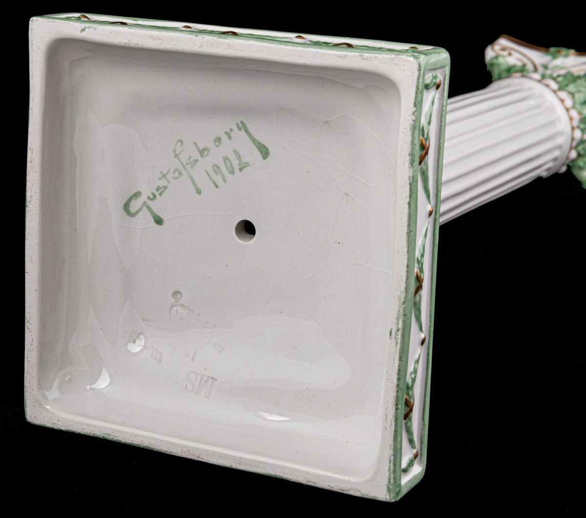 Kolonnformad ljusstake av flintgods, vit med dekor i guld och grönt.