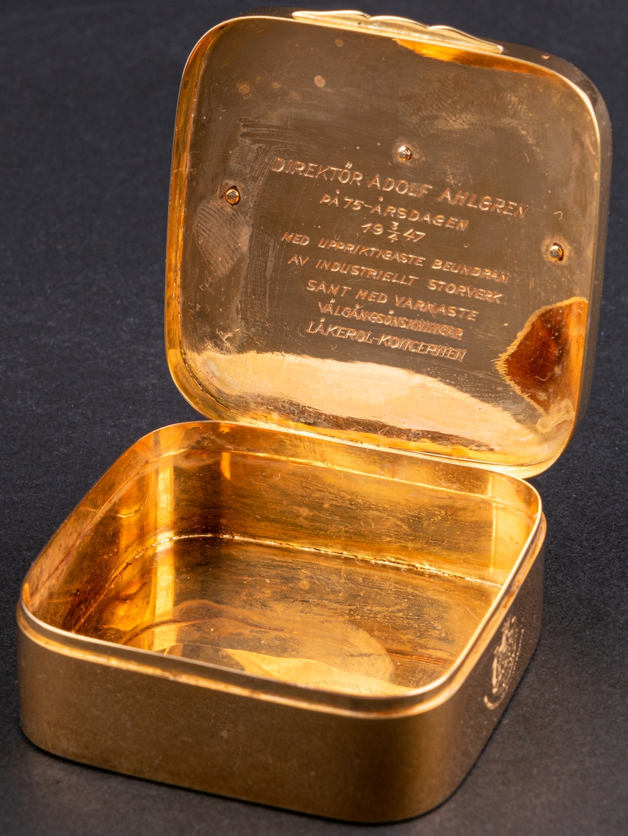 Tablettask i form av en Läkerolask, i guld med ädelstensinfattning i form av briljanter inlagda i bokstaven A på locket.