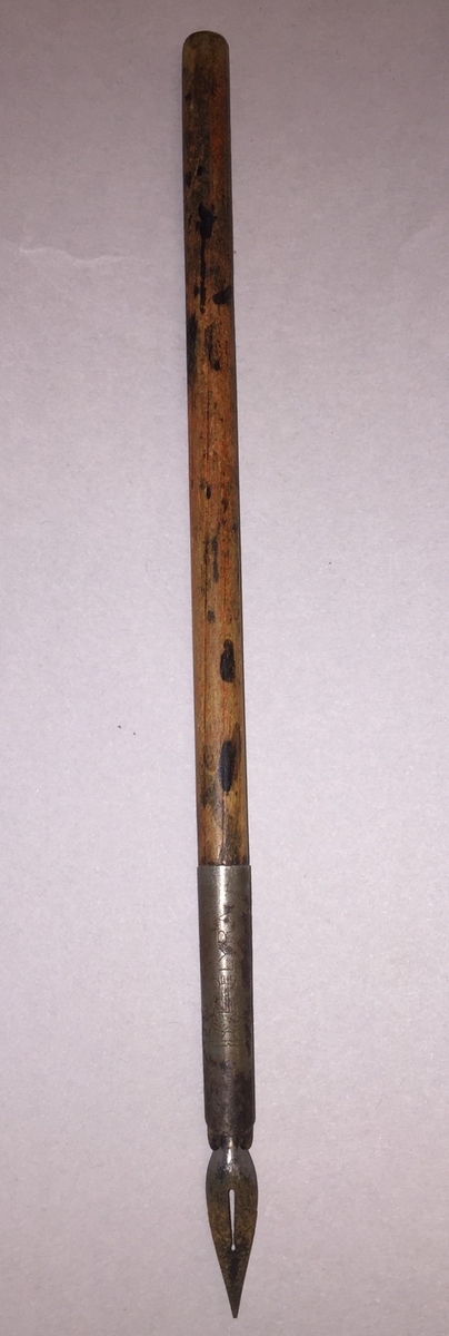 Penneskaft med spiss. Skaftet er i ubehandlatre, med blekkflekkar.