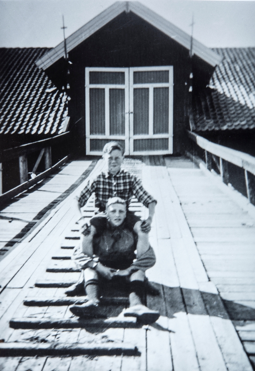 2 ungdommer sittende på låvebrua på Hjermstad gård i Stange.  g/br: 86/1. 
Odd Hjermstad (f 1925) og Arnfinn Austlid ( f 1926).