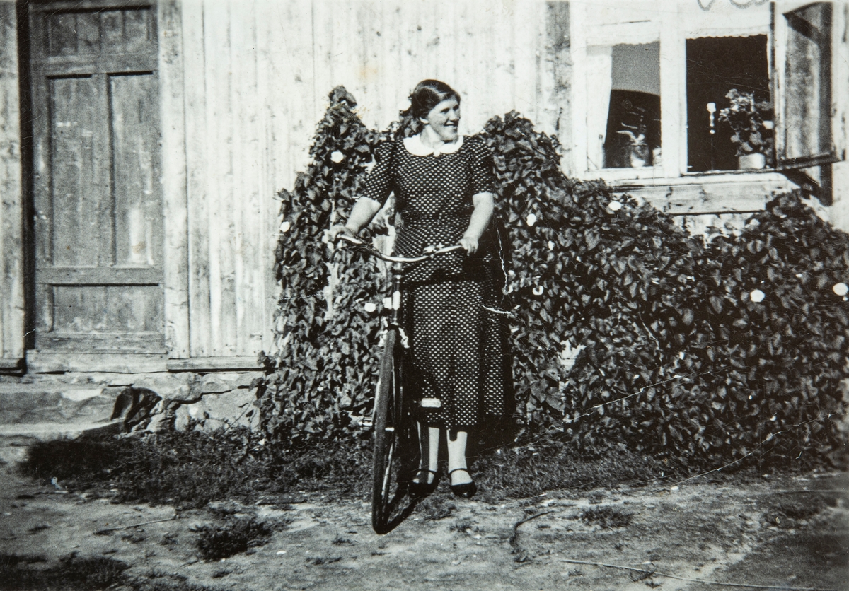 Kirsten Smedbakken, gift Rognstad. Utenfor plassen Smedbakken, under gården Holte i Stange. 
Kirsten viser stolt frem sin ny innkjøpte sykkel.
