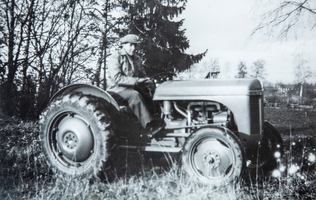Oddvar Gjestvang sittende på en gråtass traktor på gården Vestre Ottestad, Stange.