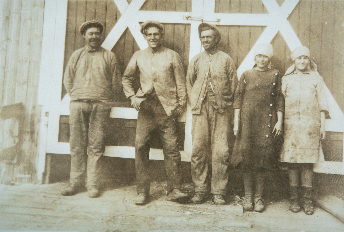 Gruppe 5. Gårsarbeidere stående foran låvedøre på Ottestad Nordre, Stange. 
Fra venstre: Johan Olsen, Gustav Gjestvang. De 3 andre er ukjent.