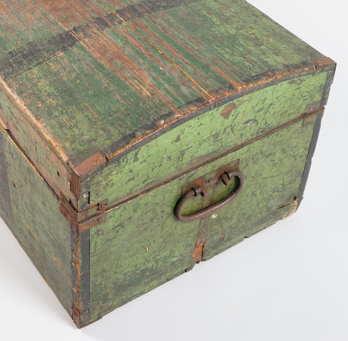 Ein grønmåla koffert i tre. Loket er forma av eit bord og er boga. Hjørna er halde saman med nokre "sinktapper" samt forsterka med metallvinkler. Kofferten har lås, og handtak i båe ender.