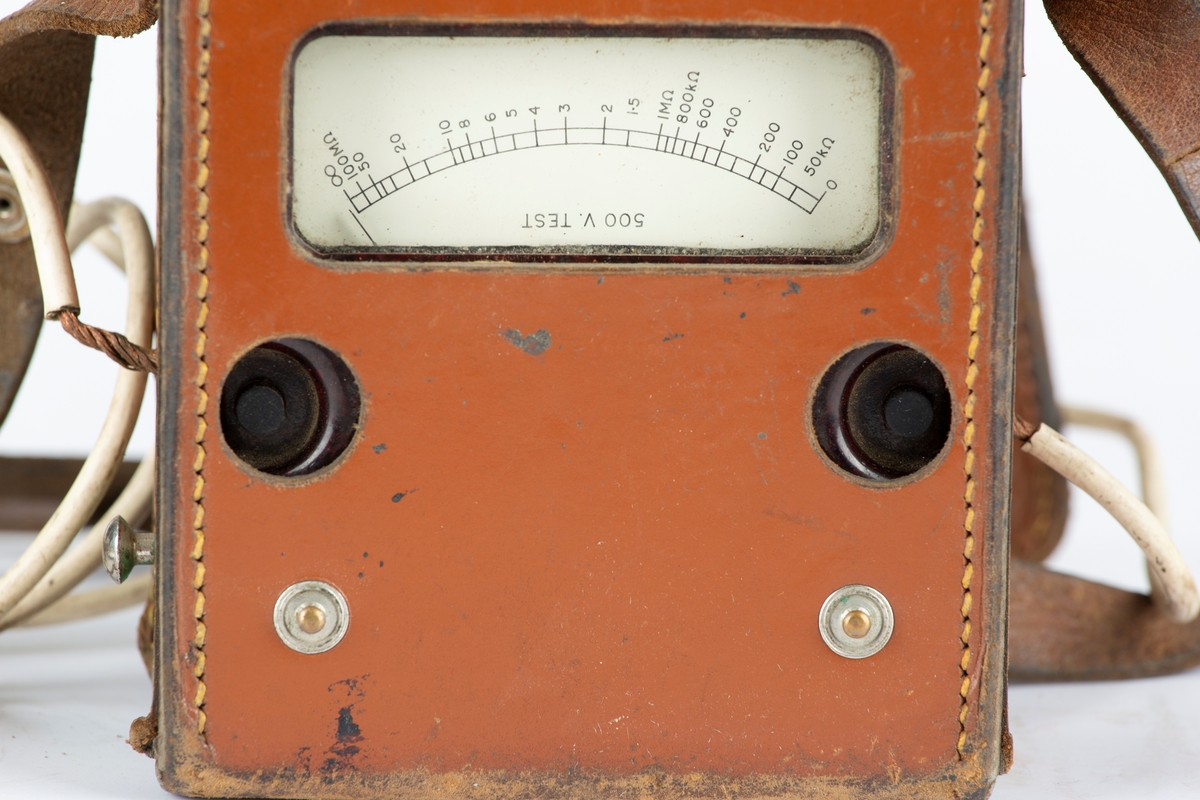 Voltmeter i læretui.To kabler med krokodilleklemmer. Måler også Ohm. Brunt etui, sort måleinstrument.