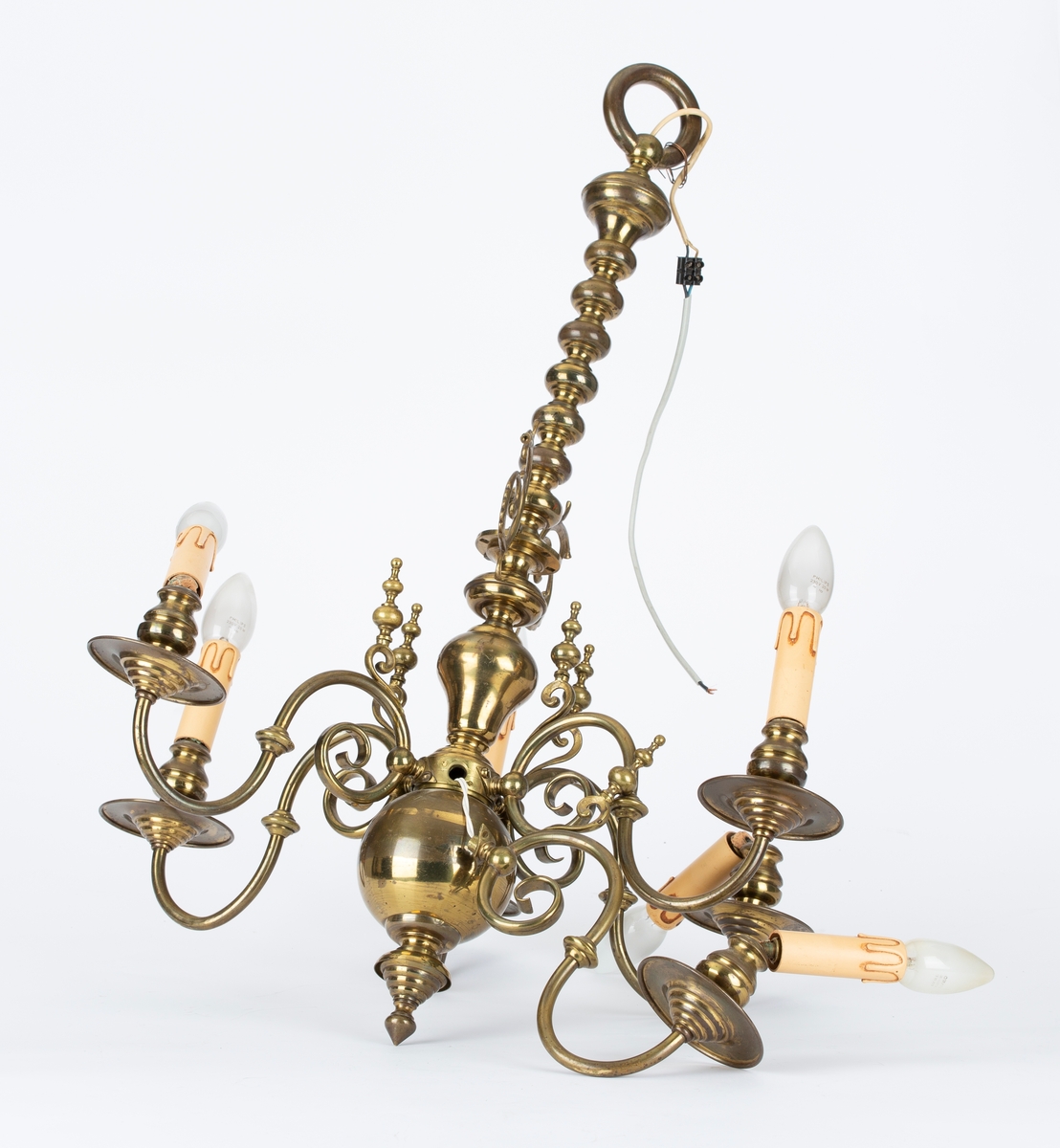 Elektrisk taklampe med 6 svungne armer med lysarmatur. Messing. 1 arm brukket. 1 lyssokkel brukket. Plasttrukket ledning.
Urneformet avslutning, opphengstang med kuleledd.