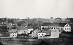 Växjö fr. nordväst, ca 1875. Man ser bl a Norrtullskolan (dåv. läroverket) med delar av kvarteren Inge och Dacke vid Skolgatan. Man kan också se Växjö stads fattiggård snett bakom skolan, till vänster. Huset revs 1907. I bakgrunden tornar Staglaberget upp sig.