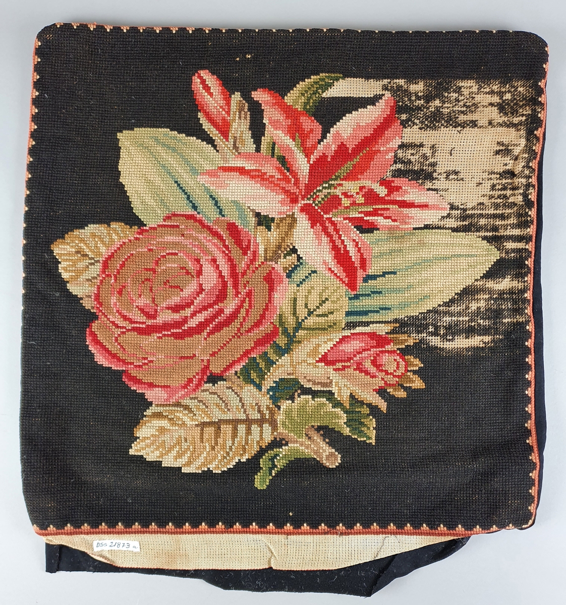 Tre broderte putetrekk med rosemotiv på svart bakgrunn. To av putetrekkene er ikke ferdig brodert.
