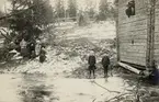 En timrad bod vid en frusen göl, 1911. Till vänster syns några kvinnor och till höger några pojkar och 
en flicka vid boden.