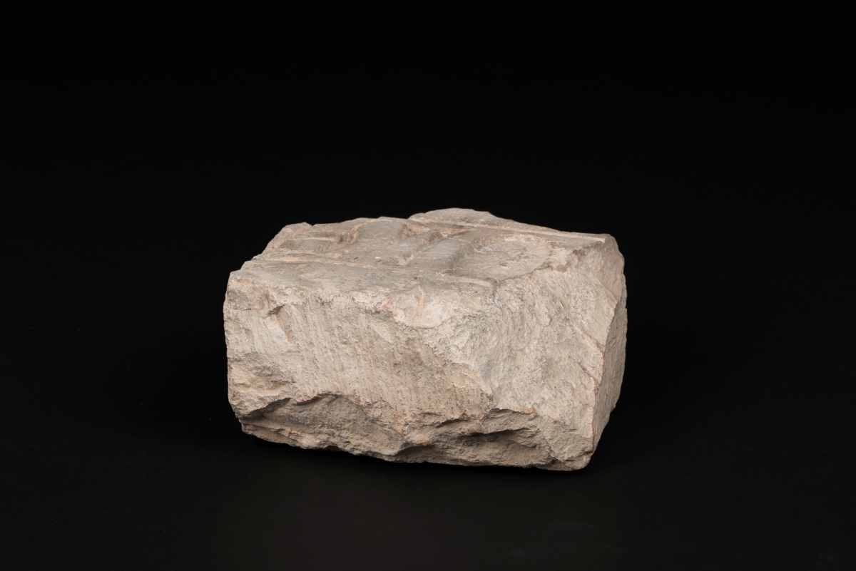 Gravstensfragment tillverkad av huggen kalksten.
Inhuggen inskrift "OLA" med nedsänkta majuskler.