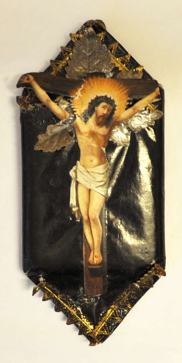 Rektangulär karamell inslagen i svart silkespapper som är krusat i ändarna. På framsidan finns ett präglat bokmärke förställande Jesus i beige färg. Skadat papper på ena sidan.