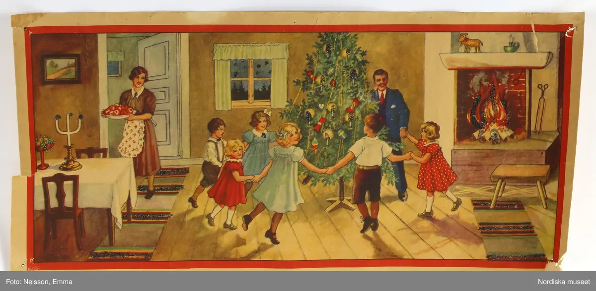 Tryckt julbonad av papper. Av Jenny Nyström. Föreställer interiör med familj som dansar runt granen. Med glitter.

Lena Kättström Höök 2019-03-21