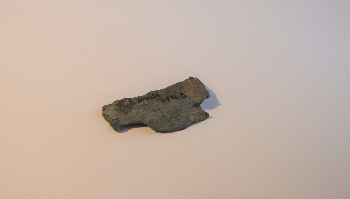 MÅL: L. 2, 8 CM H. 1, 5 CM, UREGELMESSIG, BULKET STYKKE AV TYNN BRONSEPLATE. MULIG SPOR ETTER NAGLEHULL.