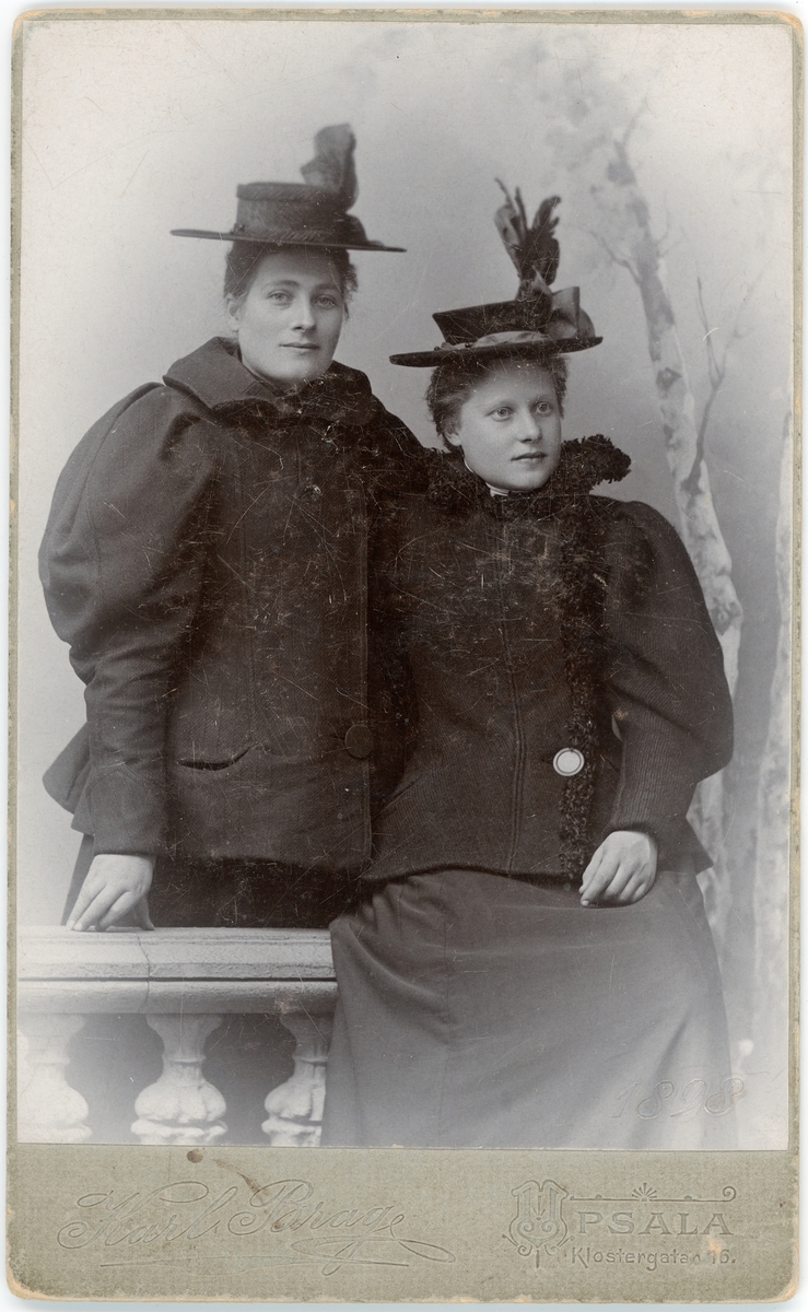 Kabinettsfotografi - två kvinnor i ytterkläder och hatt, Uppsala 1898