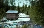 En liten stuga vid en fors.