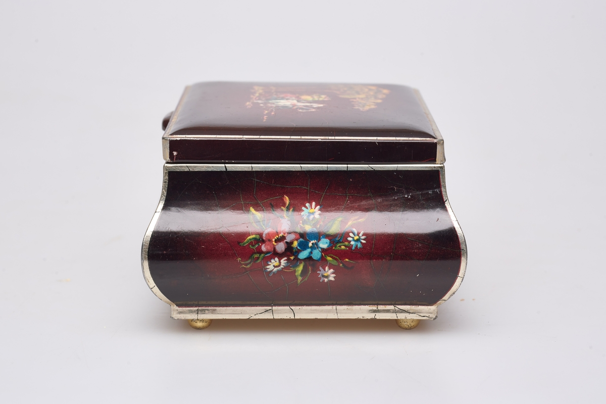 Skrinet er rektangulært, har fire små stetter, gulbrunt under, det utvider seg noe, men er likevel bare 1 cm bredere øverst enn nederst. Skrinet er brunt og har tegninger av blomster og blad. På lokket er en tegning av to hester som trekker en elegant vogn, i denne sitter glade mennesker av begge kjønn.