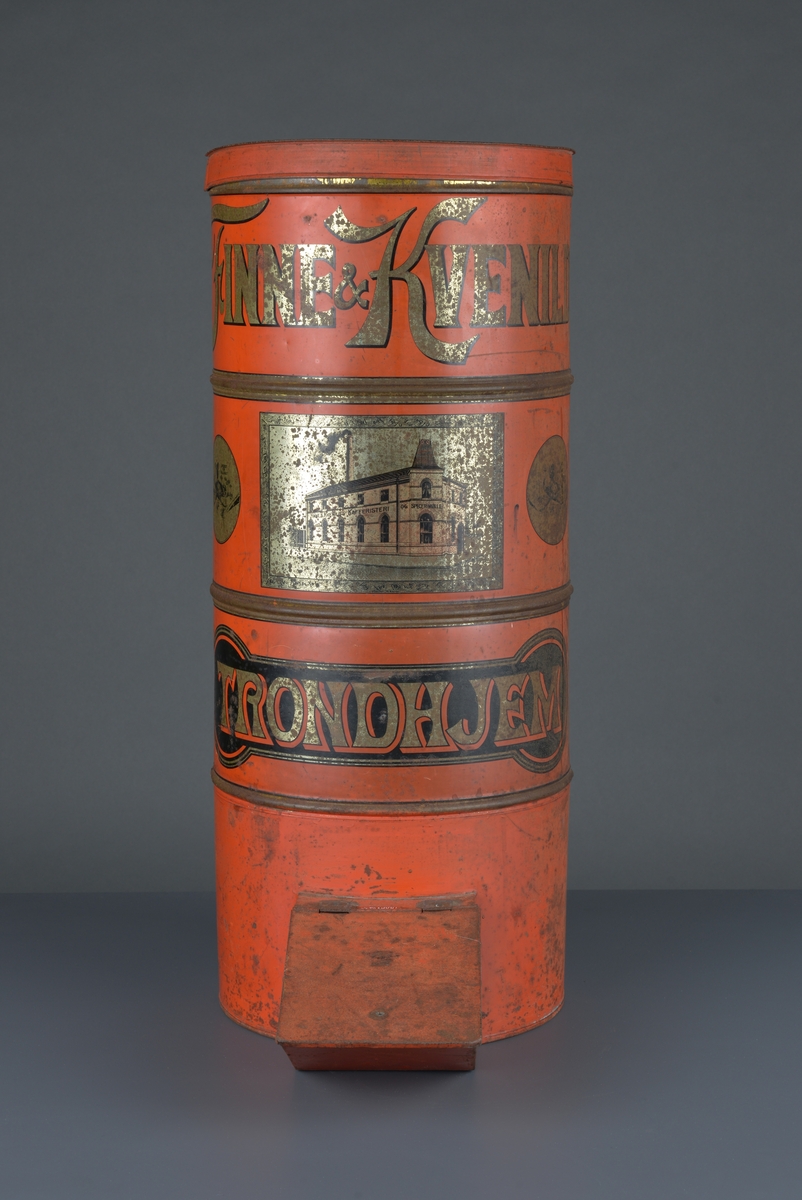 Kaffedispenser, sylinderformet, rødlakkert med reklame for Kvenild og Finne, Trondheim
Har lokk på toppen for å fylle i kaffebønner og ei luke/tut i bunnen for å hente ut kaffebønner som skal males. 

Slitt, noe rust