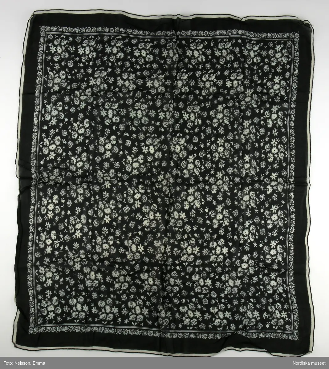 Tunn svart scarf med små vita blommor, i kanten på rad och i mittspegeln strödda.

/Magdalena Fick 2012-05-21