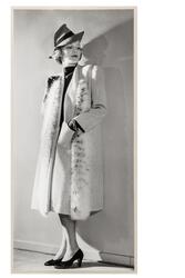 Mannekäng visar plagg i provrum. Kappa, rak, knälång med vid