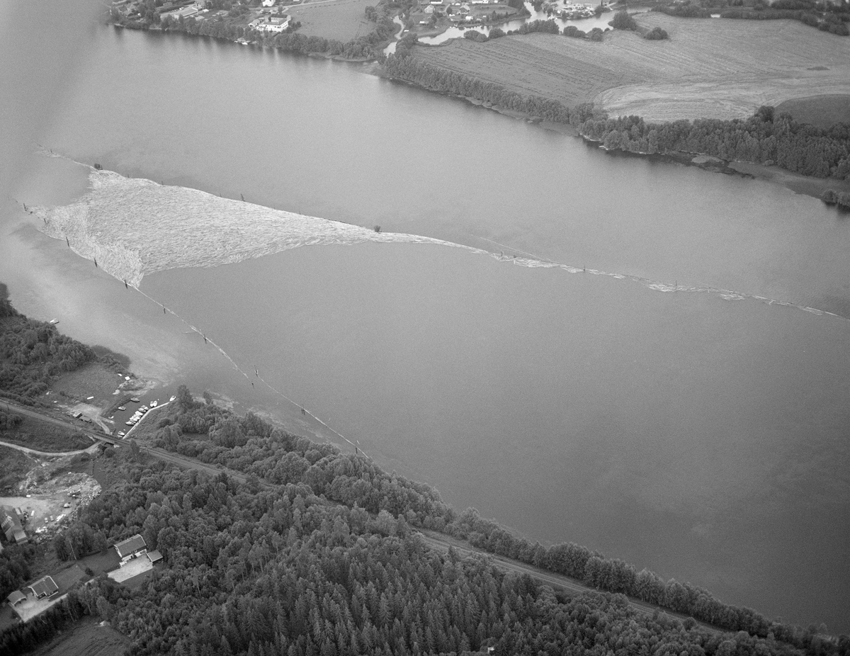 Flyfotografi, tatt over deler av lenseanlegget på Fetsund i Fet kommune, Akershus i 1985. Tømmeret ble sluppet porsjonsvis ned mot Fetsund fra attholdslensa ved Bingen, cirka åtte kilometer lengre nord. 1985 var det siste året det ble fløtet tømmer i Glomma, og dette året var det bare hovedvassdraget fra Rena i Åmot og sørover som hadde fløting. Fløtingskvantumet hadde et volum på 126 014 kubikkmeter, som var et svært beskjedent tall sammenliknet med hva som var vanlig i dette vassdraget en generasjon eller to tidligere.