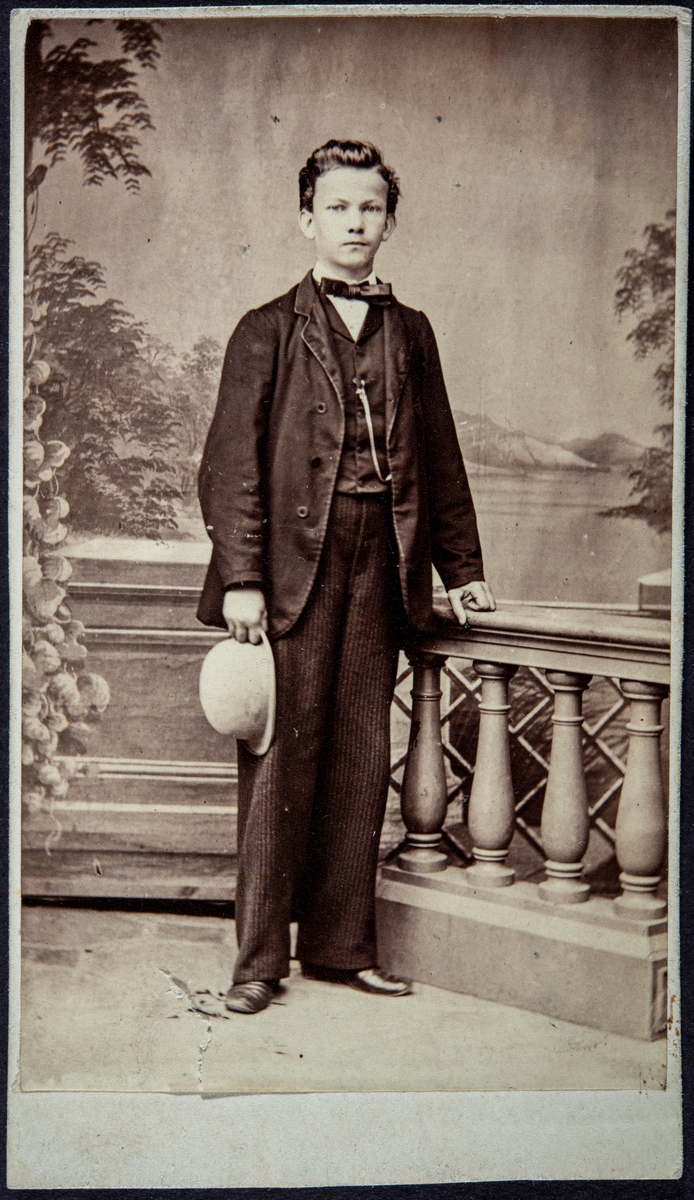 Portrett ukjent ung mann, Smestad? Dresskledd og med en hatt i hånden.