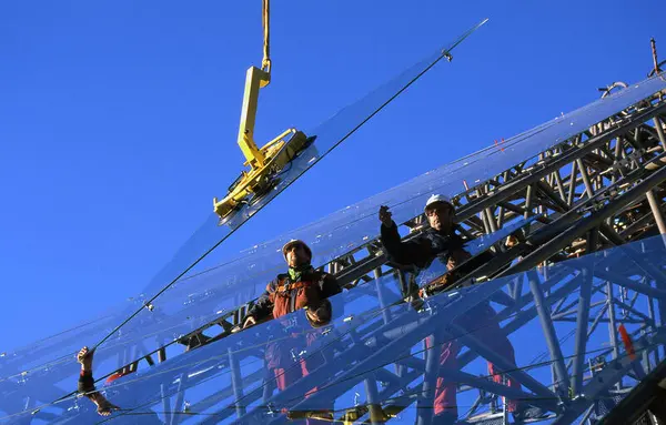 En av de 1675 glassplatene som utgjør vernebygget over domkirkeruinen på Hamar, heises på plass.