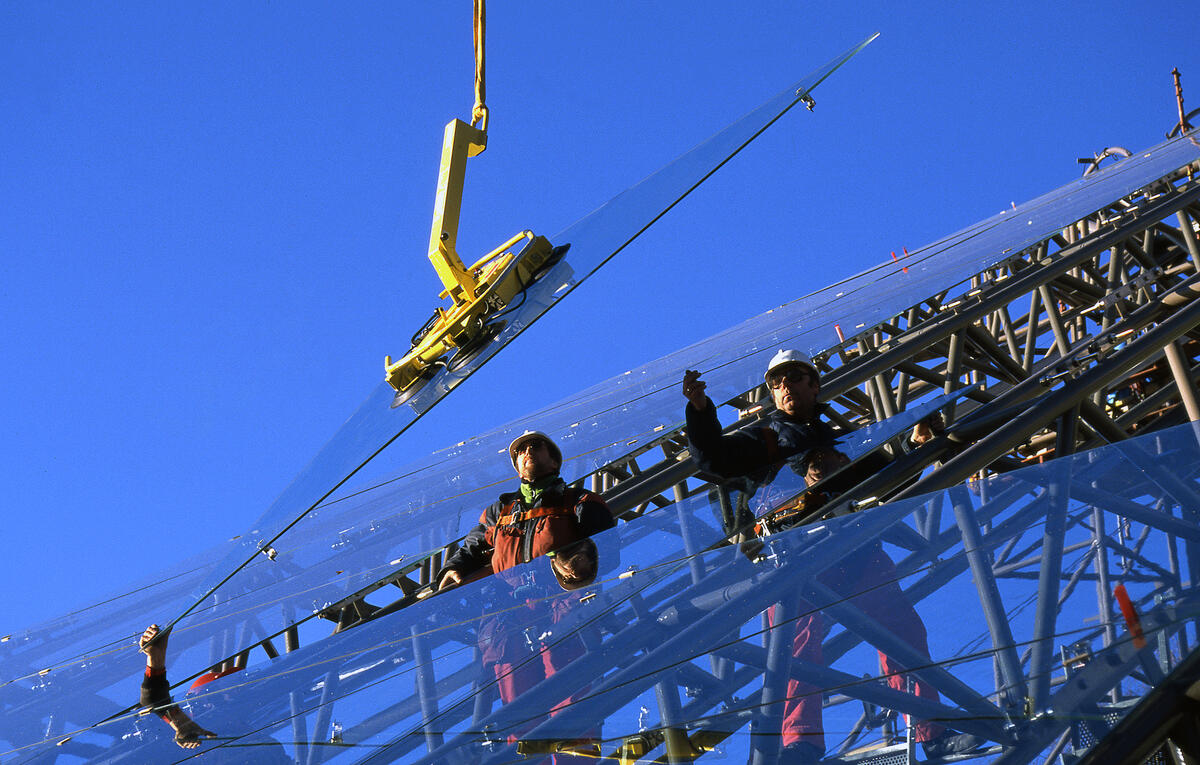 En av de 1675 glassplatene som utgjør vernebygget over domkirkeruinen på Hamar, heises på plass.