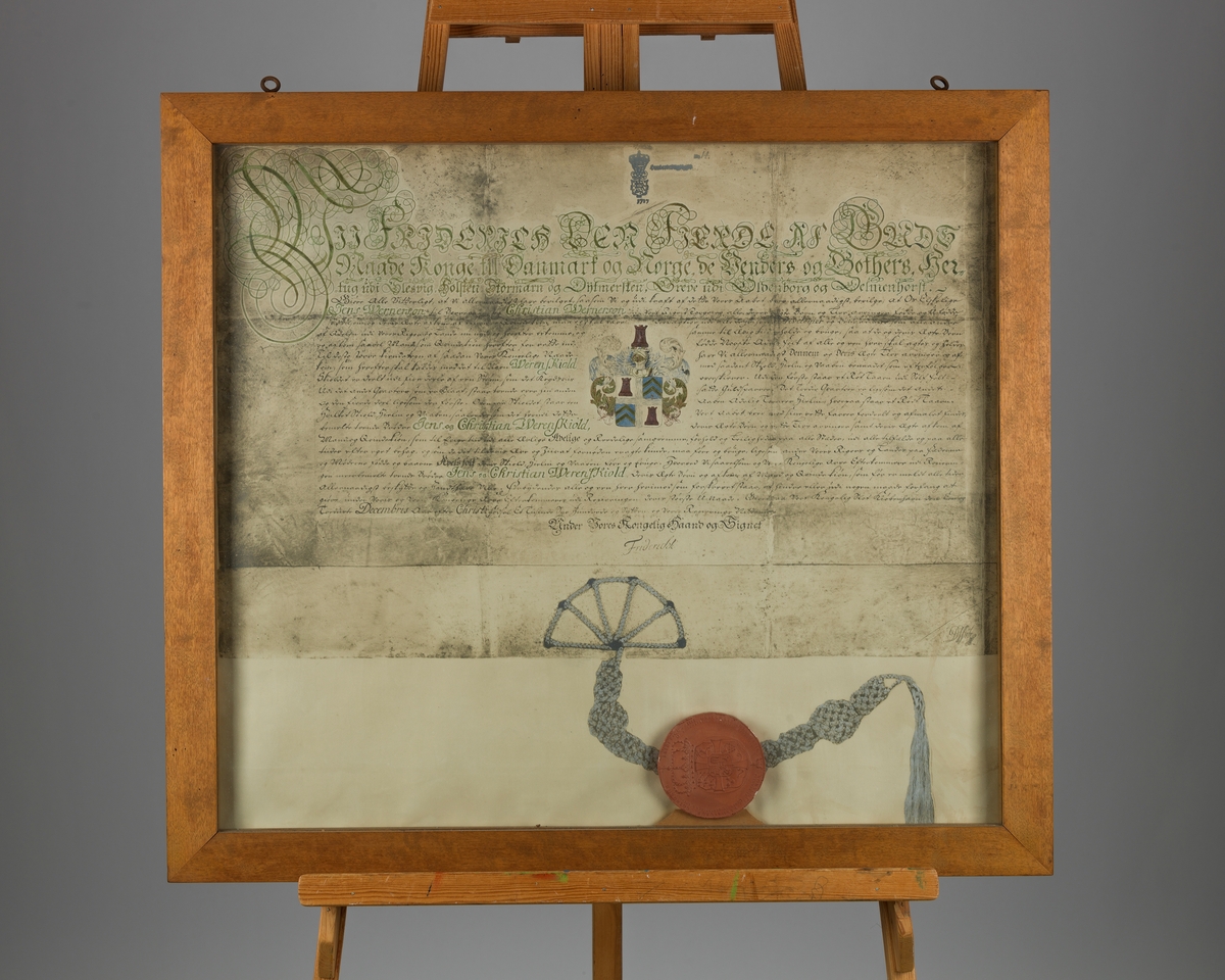 Innrammet kopi av det Werenskioldske adelsbrev fra 1717. Originalen har tilhørt brødrene Jens og Christian Werenskiold, og befinner seg i Riksarkivet. Kopien ble laget til den kulturhistoriske utstillingen i forbindelse med Østfoldutstillingen i Sarpsborg i 1930.