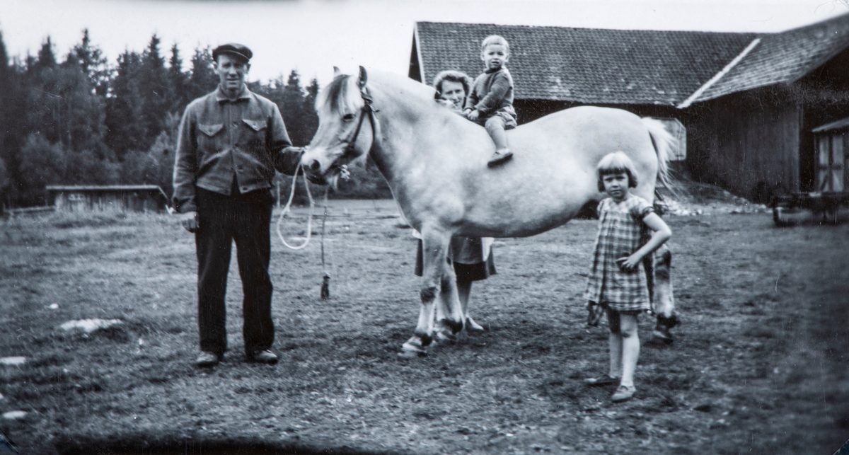På Flagstad gård, Løten. Fra venstre Ole Flagstad, Karen Flagstad, på hesten Arne Flagstad (2år), Anne Lise Nordli (6år). 
Det lille huset på venstresiden er grisehuset. På høyre side ser vi siloen og låven. Bilde er tatt i 1948.