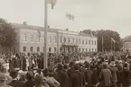 Gustaf V på besök i Växjö, 1920-tal. Man har just lämnat landshövdingens residens vid Stortorget med bil.
Mycket folk har samlats.