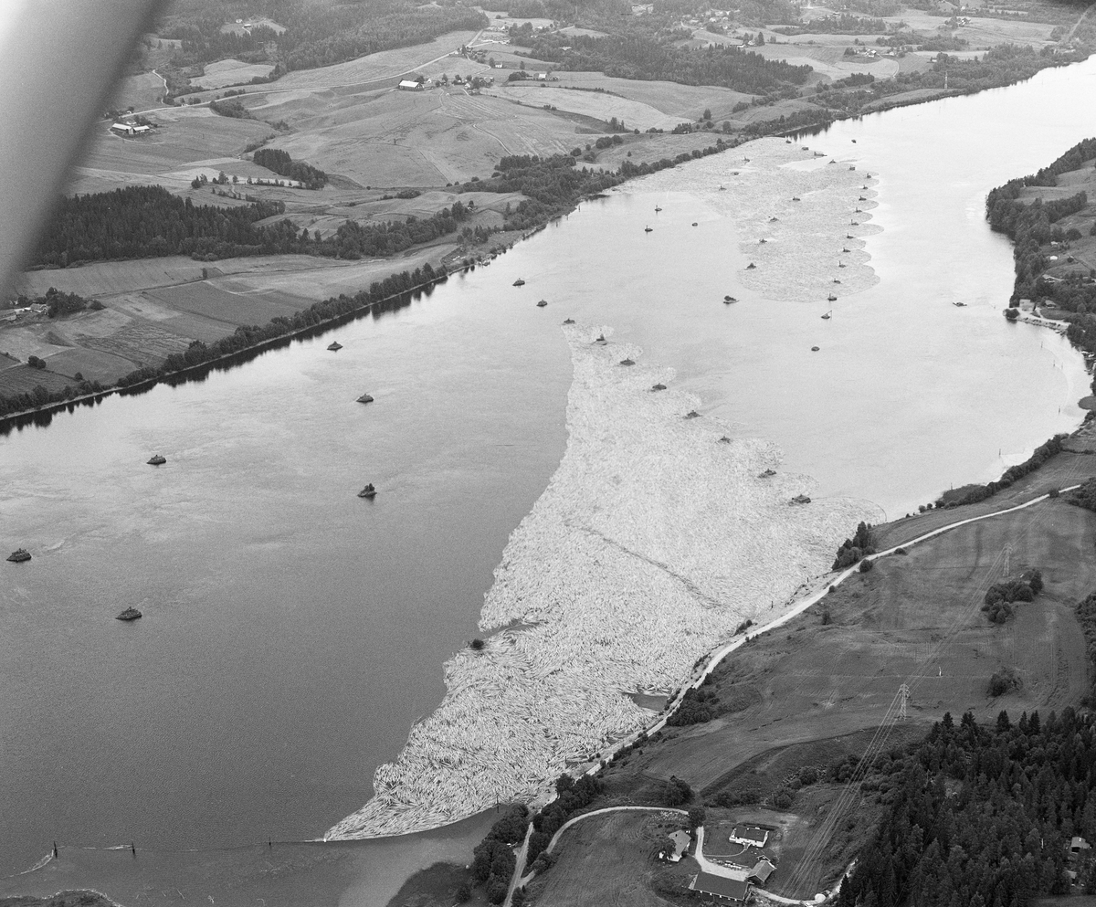 Flyfotografi, tatt ned mot Bingen lenser i Glomma, Sørum, Akershus. Denne kunstruksjonen skulle samle opp og holde på løstømmer som kom flytende fra ovenforliggende distrikter. Fra gammelt av lå sorteringslensa der tømmer som skulle til sagbrukene på Nedre Romerike ble skilt fra det som skulle videre mot brukene i Nedre Glomma. Fra 1861, da den nye sorteringslensa nedenfor jernbanebrua ved Fetsund ble satt i drift, ble anlegget ved Bingen ombygd til et reservoar, der tømmeret ble samlet for deretter å bli sluppet i høvelige dagsrasjoner videre nedover til sorteringsanlegget 6-7 kilometer lengre nede ved elveløpet. Utover sommeren og høsten kunne tømmerbeholdningen i attholdslensa ved Bingen være på flere millioner stokker. I dette området, nedenfor Bingsfossen, der elva var stilleflytende, fantes det 51 lensekar. Det dreide seg om steinfylte tømmerkister, som var fornkringspunkter for lensa som holdt igjen tømmeret som etter hvert skulle slippes ned mot sorterings- og moseanlegget ved Fetsund lenser. Fotogrfiet er tatt i motsrøms retning, fra en posisjon like sør for kommunesenteret Sørumsand. Kar. Tømmerkar.