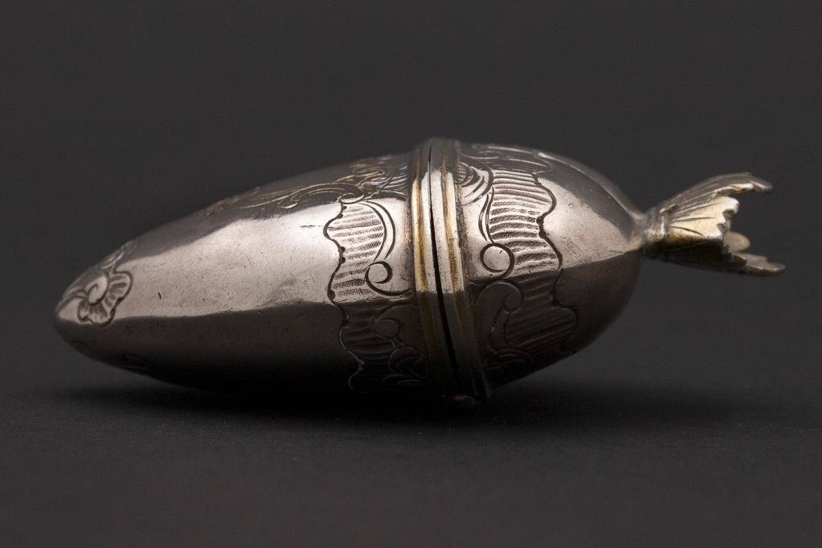 Hjerteformet luktevannshus i sølv uten fot. Delvis gjennombrutt, åpen, forgylt krone med strekgravyr på lokket. Gravert rokokko-ornamentikk på korpus; kartusj med rester av forgylling på forsiden. Forgylt kant rundt åpningen og innvendig forgylt.