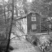 Motiv från Sandbäcksgatan 14 i Linköping. Bostadshuset uppfördes i Tinnerbäcksravinen under 1900-talets första år och placerades som synes alldeles intill bäcken. Här dokumenterat 1968 inför planerad rivning, vilket emellertid kom att dröja till början av 1970-talet.