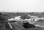 Vy från Tannefors sluss mot Linköpings stad. Till höger om slussen ses dammarna till stadens första vattenverk.
Anm: Fotografen har själv daterat fotografiet till år 1901. Den observante kan emellertid se att, sedermera, Linnéskolan är under uppbyggnad. Skolan stod i själva verket klar 1898.