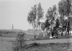 Linköping från Ramshäll. I fonden ståtar den vid tiden nyligen uppförda Folkskolan, sedermera Linnéskolan. I grönskan till vänster om barnen skymtar villa Boiro, uppfört av telegrafkommisarien Emrik Wenström 1898.