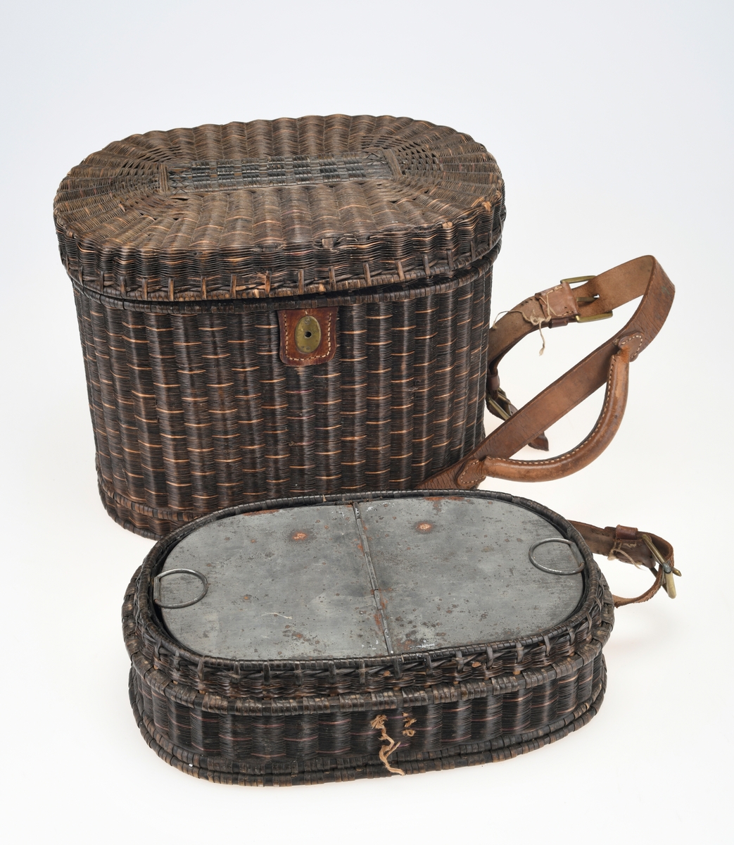 En piknikkurv med følgende innhold: 1 matboks, 2 større vannglass, 2 mindre vannglass, 4 hvite tallerkener, 4 kniver, 4 gafler og 1 beholder for salt/pepper. Kurven er flettet av pil eller lignende tre og er i ulik nyanser av brunt. Kurven er todelt, og i den nederste delen er det plass til matboksen, mens i den øverste delen det øvrige av piknikkutstyr. Beggel delene er foret med tesktil som er behandlet med granitol og deretter farget grønt. Langs kanten oppe (i begge delene) er det en svart tungekant av skinn. I den øverste delen av kurven er det festet strikk i lokket og i sidene i kurven for å feste utstyr. Det er også laget fire rom for å sette piknikkutstyr i. Rommene er laget av tekstil behandlet med granitol og farget grønn. Utvendig er det lærreimer som holder under- og overdel sammen samt fester lokket. De har spenner av messing og er dermed justerbare. I front er det et lite beslag med lås i messing. I den nederste deln av kurven er det plass til en oval matboks av blikk. Den har runde håndtak i hver side. Lokket er todelt og hengslet på midten slikk at lokkene åpnes mot midten. Inni boksen er det en skillevegg. Resten av utstyret er i "hovedkurven". Det er fire (vann)glass der i to forskjellige størrelser.  I de to største glassene er det en 1,5cm bred strikk som hindrer gnisning når de to mindre glassene er plassert i de to større. I tillegg er det fire hvite, enkle tallerkener. De har stempel på undersiden. Kurven innholder fire kniver og fire gafler. Knivene har avrundet blad av stål og svart trehåndtak. Gaflene har tre tinder av stål og svart trehåndtak. Til sist er det en beholder for salt og pepper. Den er av svart tre med dreid knopp på toppen. Skrur man av den øverste delen er det beholder for pepper. Skrur man av den nederste delen er det beholder for salt.