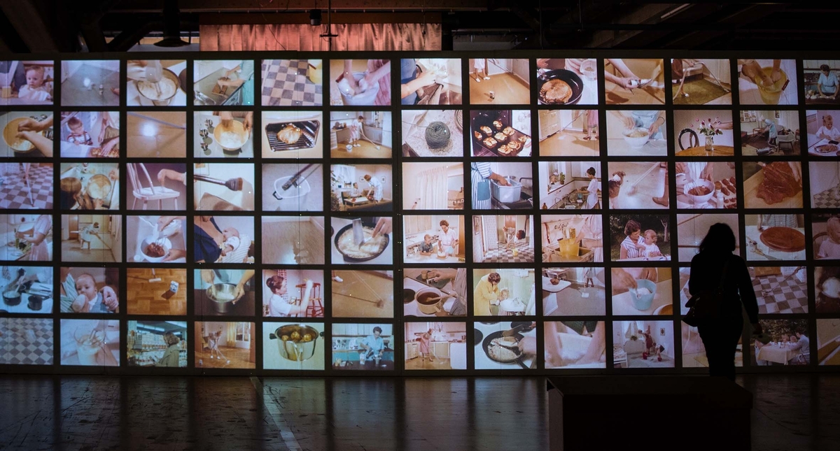 Installation med loopade filmsekvenser av hushållsarbeten från Husmors Filmer AB från åren 1956-1961.