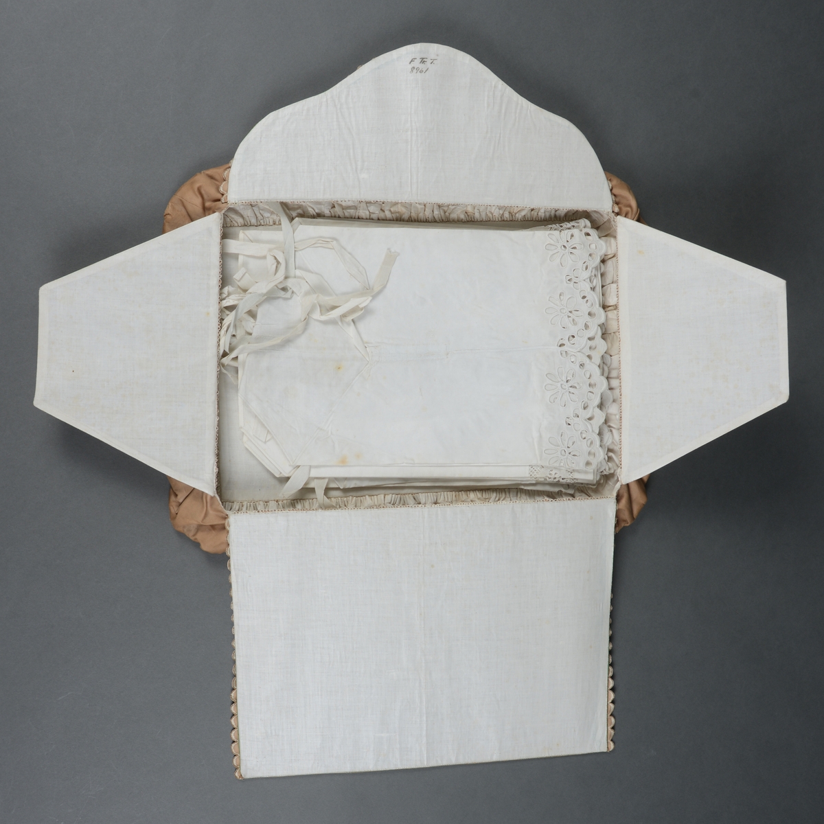 Rektangulær mappe med gjennomhullet broderi, "Venetiansk søm". Bunnen og lokkdelen er avstivet med en papp-plate, foret med hvitt chintzstoff. Sidene er av sammenrynket stoff som er sydd til bunnen og lokkdelene for hånd. Sidene er foret med samme stoff som bunn og lokkdelene. Under de broderte delene er det trekt med grønt silkestoff. Mappen inneholder 5 1/2 par mamelukker. 
Mamelukk 07, 1 singel, har brodert tungekant og engelskbroderi, håndsydd søm på utsiden og indresøm på innsiden av mamelukken, 2 knyttebånd.
Mamelukker 08, 1 par, har brodert tungekant og engelskbroderi, håndsydd, indresøm på ut- og innsiden av mamelukken, opprinnelig 2 knyttebånd på hver.
Mamelukker 09, 1 par, har innfelt mellomverk av kniplinger, 1 knyttebånd på utsiden i øvre kant, sømmene er håndsydde, indresøm på innsiden.
Mamelukker 10, 1 par, påsydd engelskbrodert kant, søm på innsiden av mamelukken, håndsydd, 2 knyttebånd på hver.
Mamelukker 11, 1 par, har brodert tungekant og engelskbroderi, håndsydd, indresøm på innsiden, opprinnelig 2 knyttebånd på hver.
Mamelukker 12, 1 par, påsydd engelskbrodert kant, søm på innsiden av mamelukken, håndsydd, 2 knyttebånd på hver.