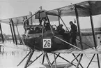 Flygplan FF 49C nummer 26 på vatten, 1920-1925. Förberedelse för start. Flygförare på plats och två militärer på vingarna om varsida av flygplanet.