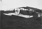 Havererat flygplan Thulin FA nr 866 på Bonarpshed. Besättning Tor von Johnstone och Ragnar Ragnarsson omkom vid ett landningshaveri den 12 augusti 1918, då flygplanet vek sig. Människor i rörelse kring flygplanet.