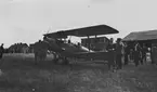 Flygplan De Havilland DH. 82, Tiger Moth, tillhörande norska flygvapnet står vid F-hangaren på flygfältet på Malmen, 1930-tal. Folksamling runt omkring.