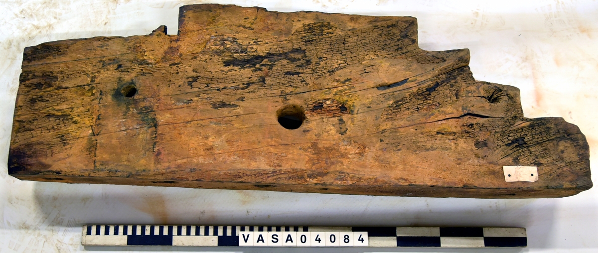 Lavettsida höger med tre trappsteg. Bit framför axelläget är borta. Torkad, missfärgat, svårt skadad på främre hörn. 
 

Right gun cheek. Dried, discoloured, heavely damaged on front top corner. Remounted  with hardware.