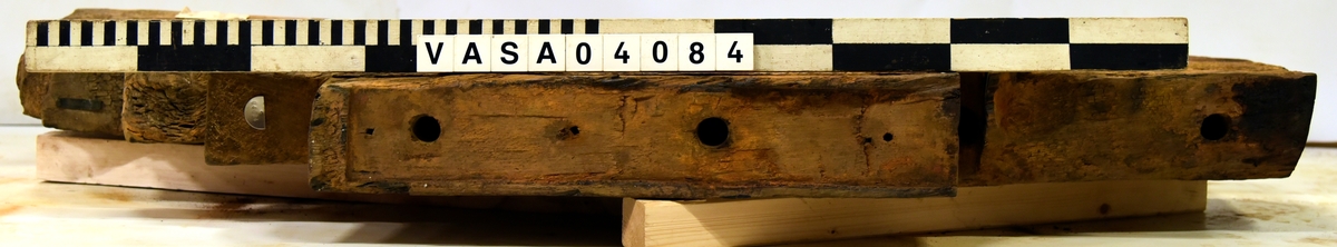 Lavettsida höger med tre trappsteg. Bit framför axelläget är borta. Torkad, missfärgat, svårt skadad på främre hörn. 
 

Right gun cheek. Dried, discoloured, heavely damaged on front top corner. Remounted  with hardware.