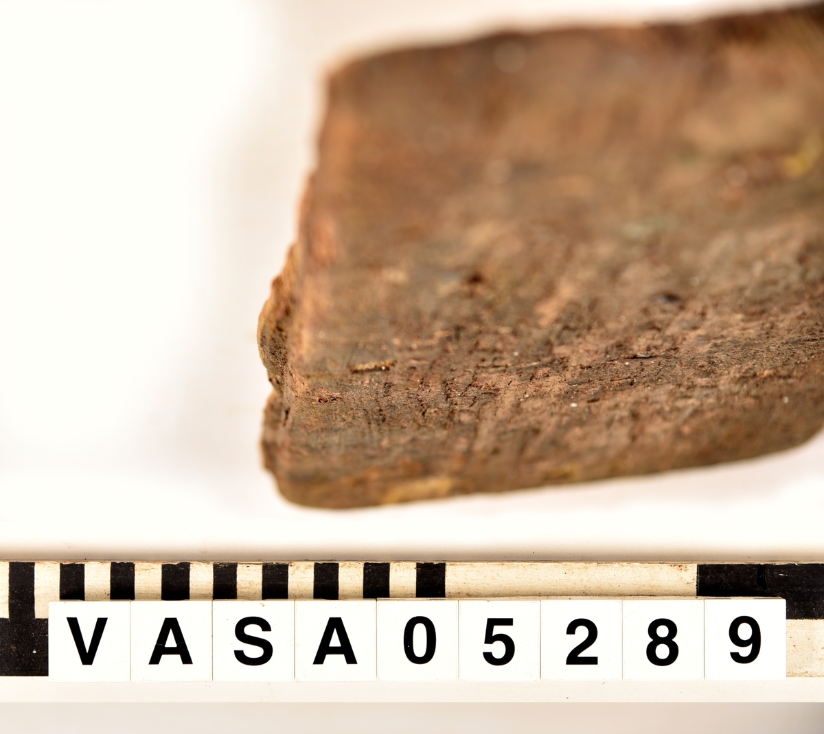 Bräda med snedvinklad ändar. Falsade på en långsida med tapporna på en kortsida. Ett spikhål (synliga bara på ena ytan).
Avbruten på falsar och tappor, Avbruten på andra långsidor (längs spikhål.) Mjuk, flagig och vittrad. Mycket saltskadat.
