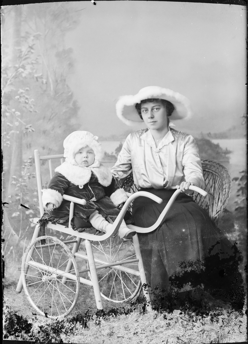 Ateljéporträtt - kvinna med litet barn som sitter i vagn, Östhammar, Uppland