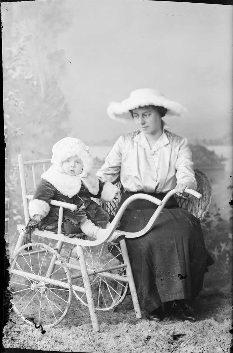 Ateljéporträtt - kvinna med litet barn som sitter i vagn, Östhammar, Uppland