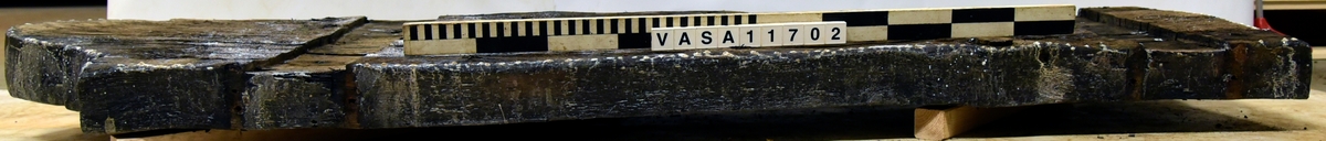 Lavettbotten, flertal sprickor med splitter, stor trä knut i mitten.

För mer information se Dokumentationsblankett under Referenser – Länkade filer.

Text in english:
Heavely cracked split gun-bed, large central knot.

For more information see the Documentation form under References – Linked files.